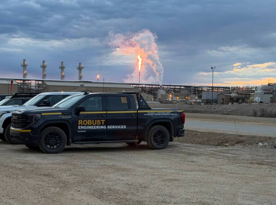 Black Robust Engineering Services pickup truck parked at industrial site with flare stack and pipes at Cenovus Christina Lake during monorail commissioning